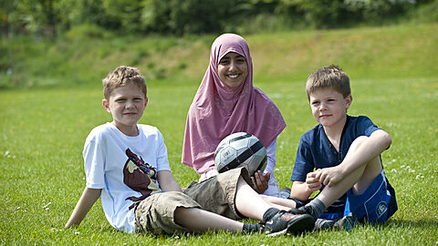 Three happy children sitting in a park